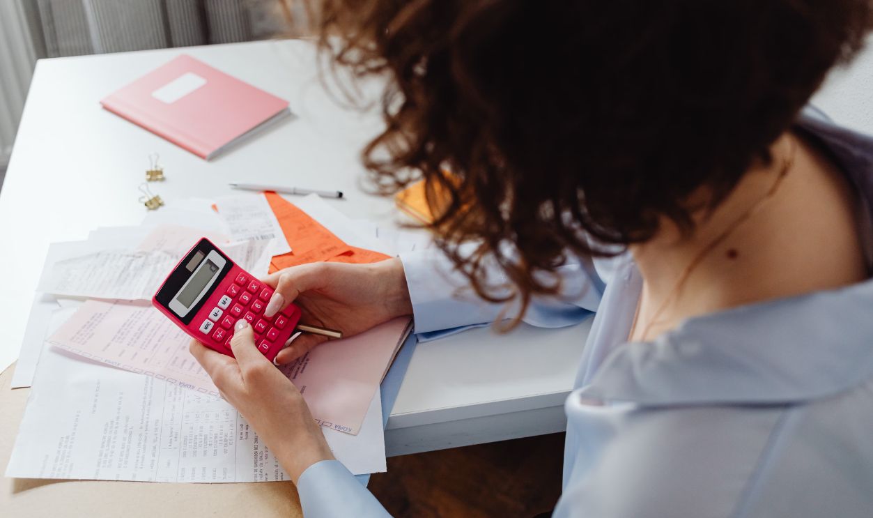 Woman calculating expenses with documents and calculator at work desk