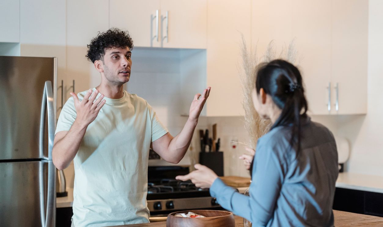 A couple in a tense conversation in a modern kitchen, expressing emotions.