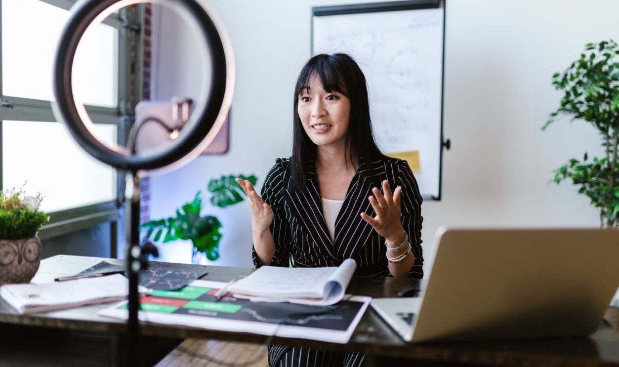 Female vlogger recording a professional video with a ring light setup, discussing finance topics.
