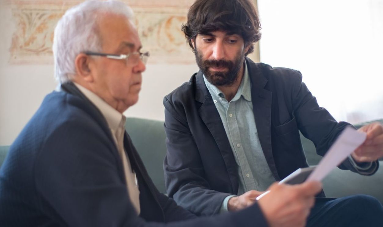 Two men engaged in a business consultation, reviewing documents in a professional setting