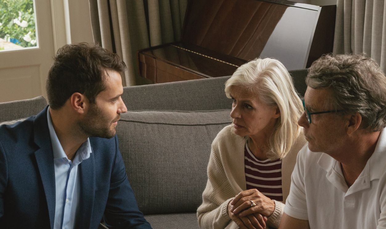 High view of active senior Caucasian couple discussing with real estate agent in living room at home