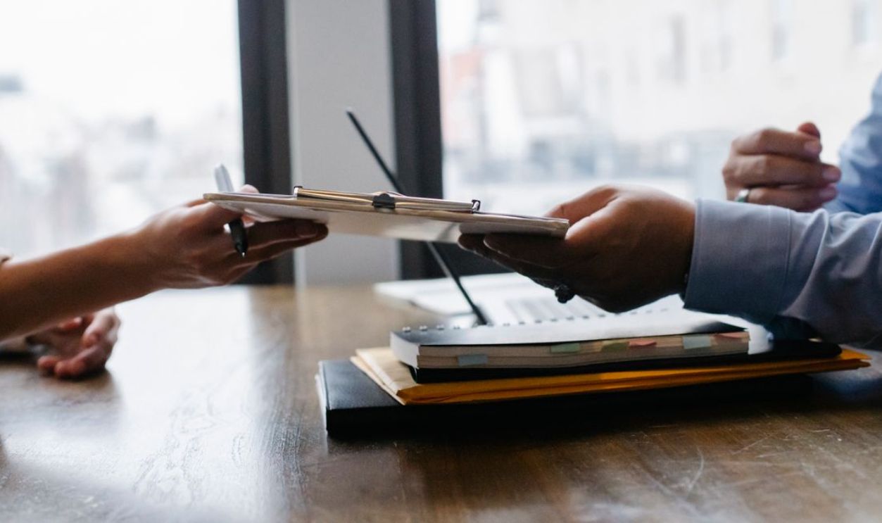 Hands exchanging documents during a professional meeting in an office environment