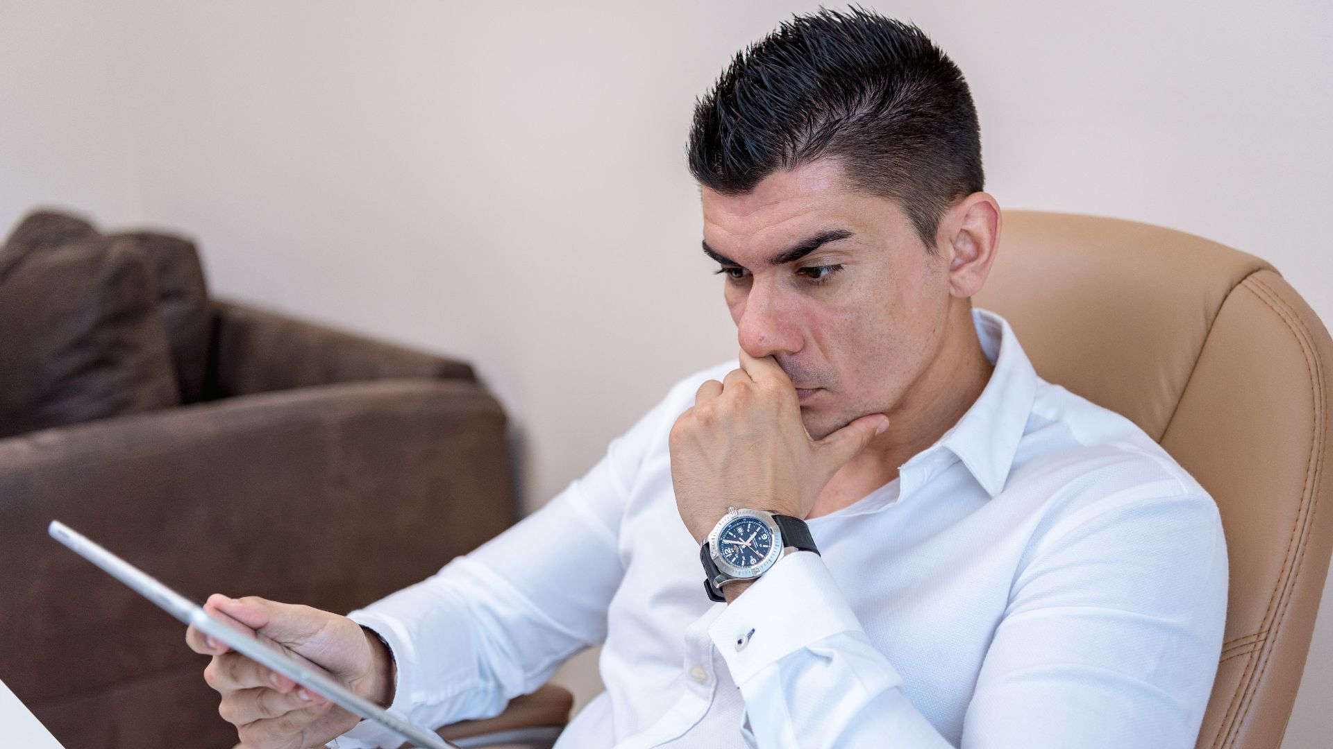 Man in white shirt intently using a tablet in a contemporary office setting.