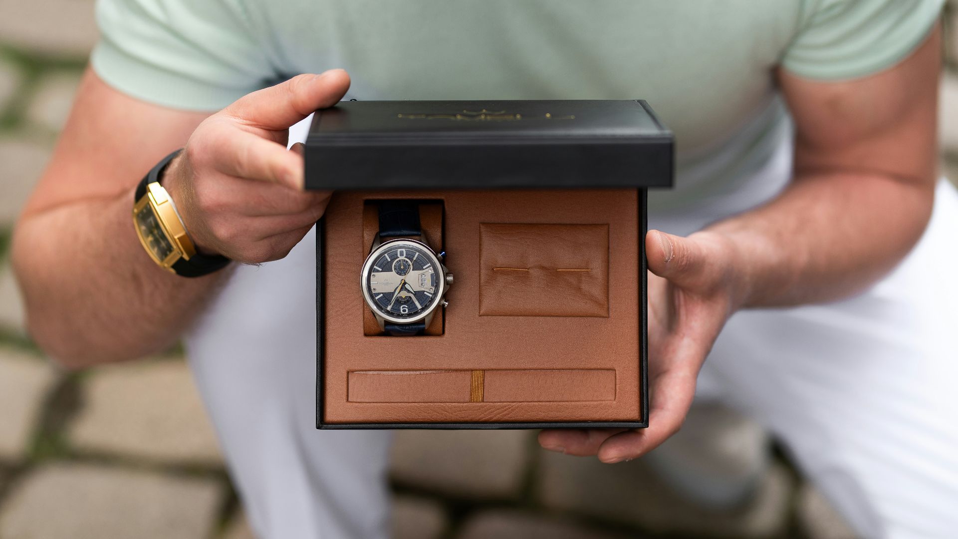 A man is holding a watch in a box