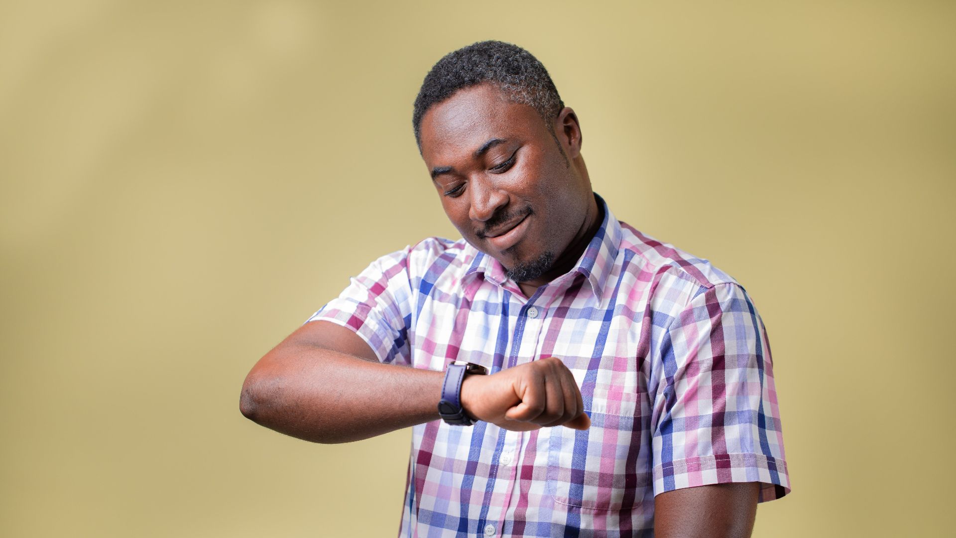 Portrait of a man checking his wristwatch, set against a yellow background, conveying a sense of time awareness.