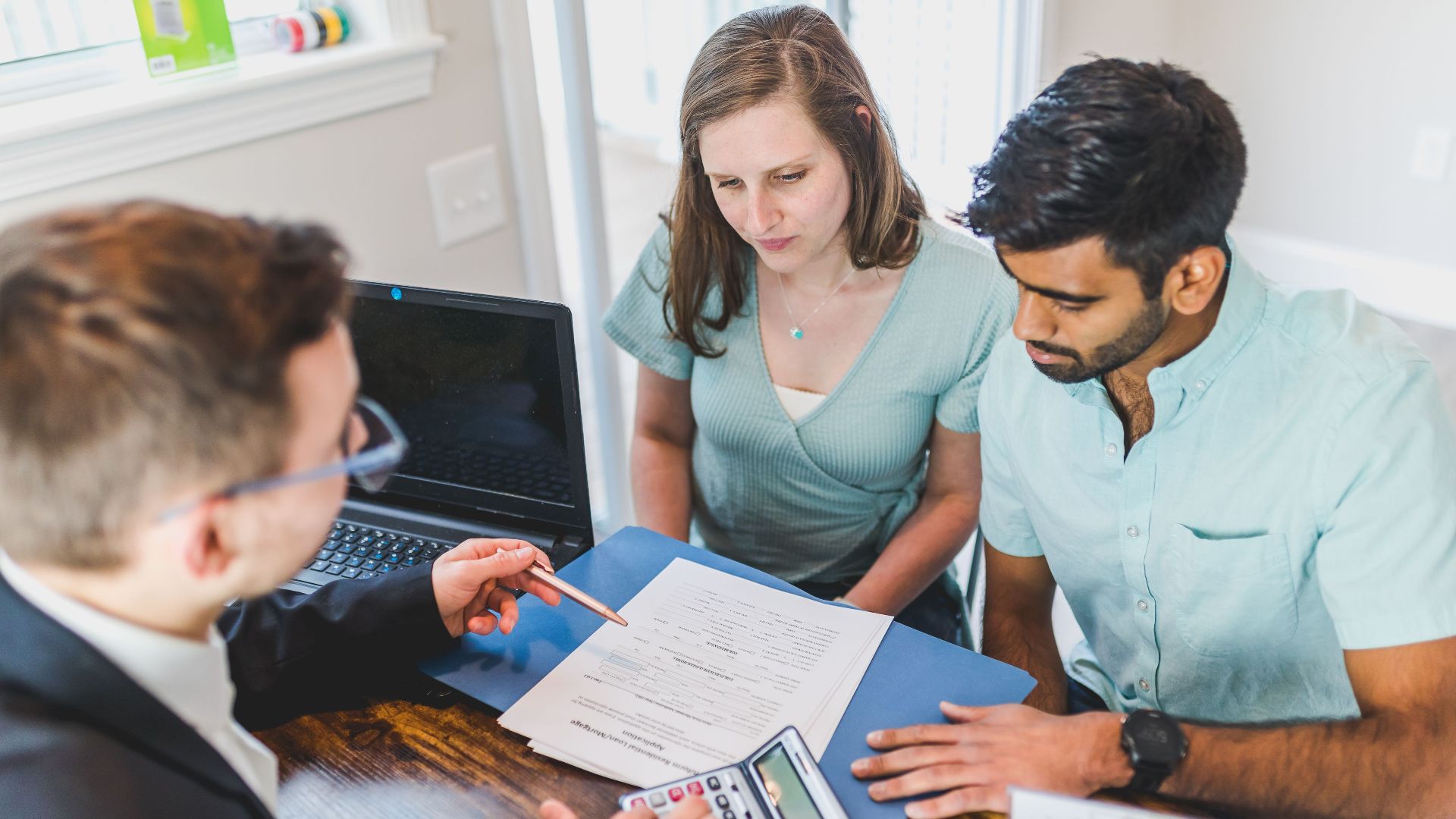 Young couple meeting with real estate agent to discuss property purchase.