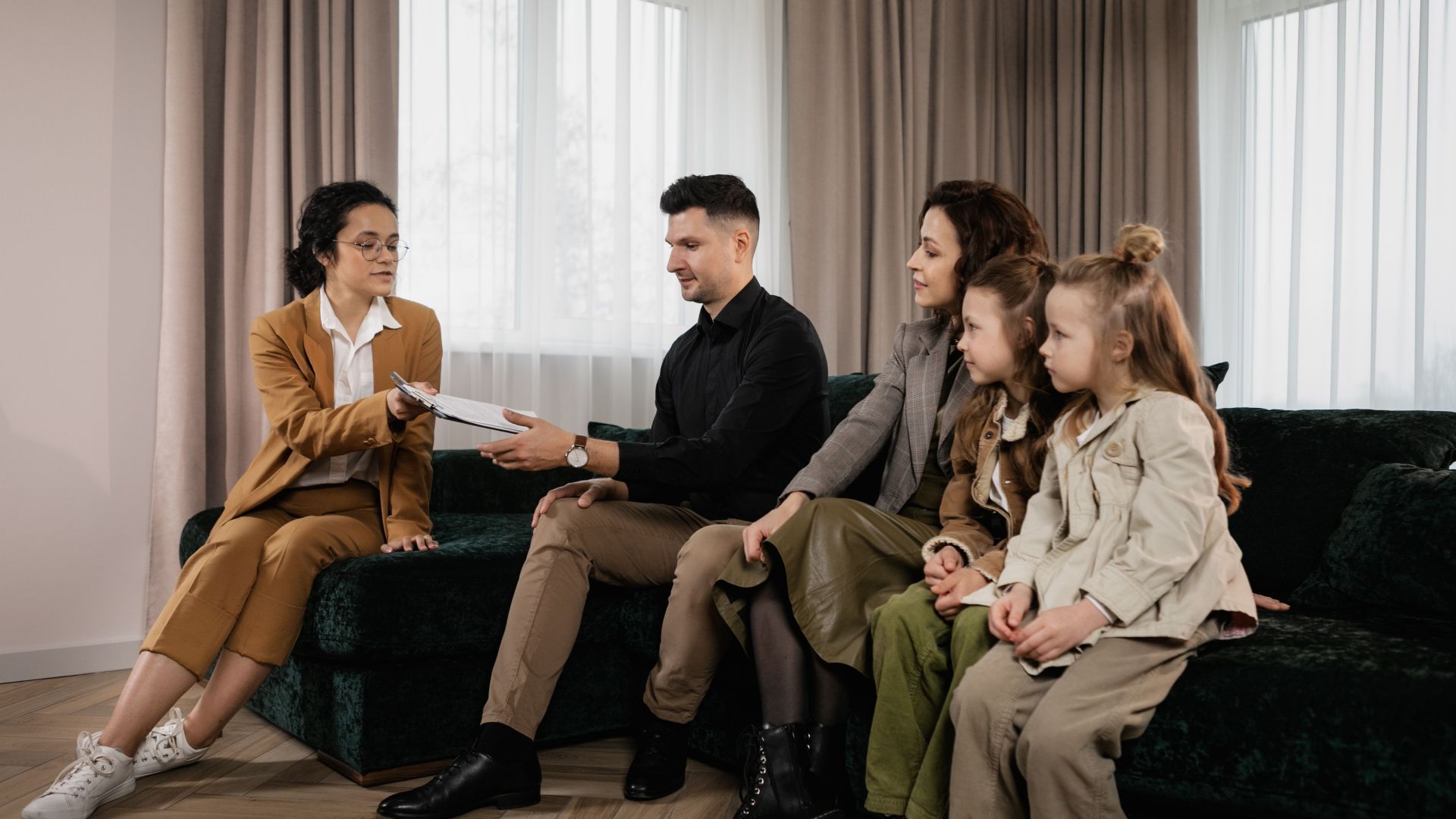 A family meets with a real estate agent in a stylish living room, reviewing documents for a potential home purchase.
