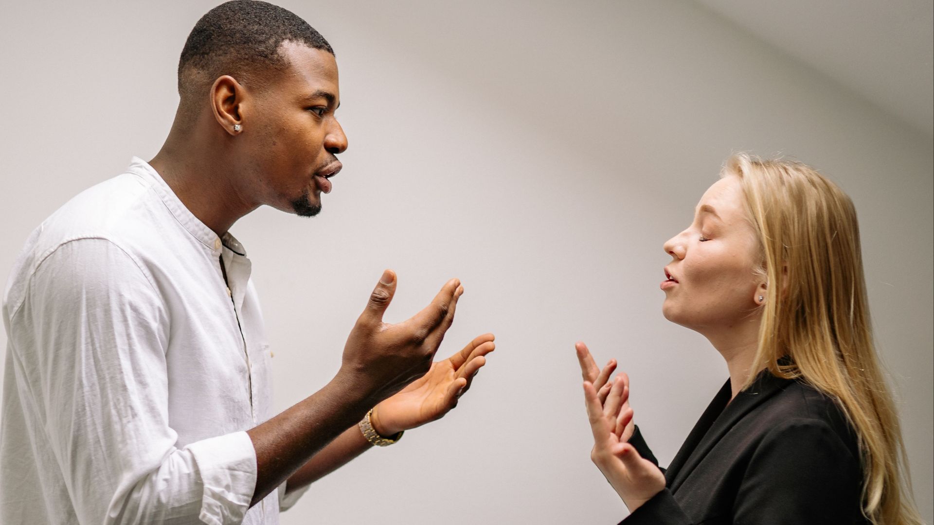 A couple engaged in a heated argument indoors, expressing strong emotions and gestures.