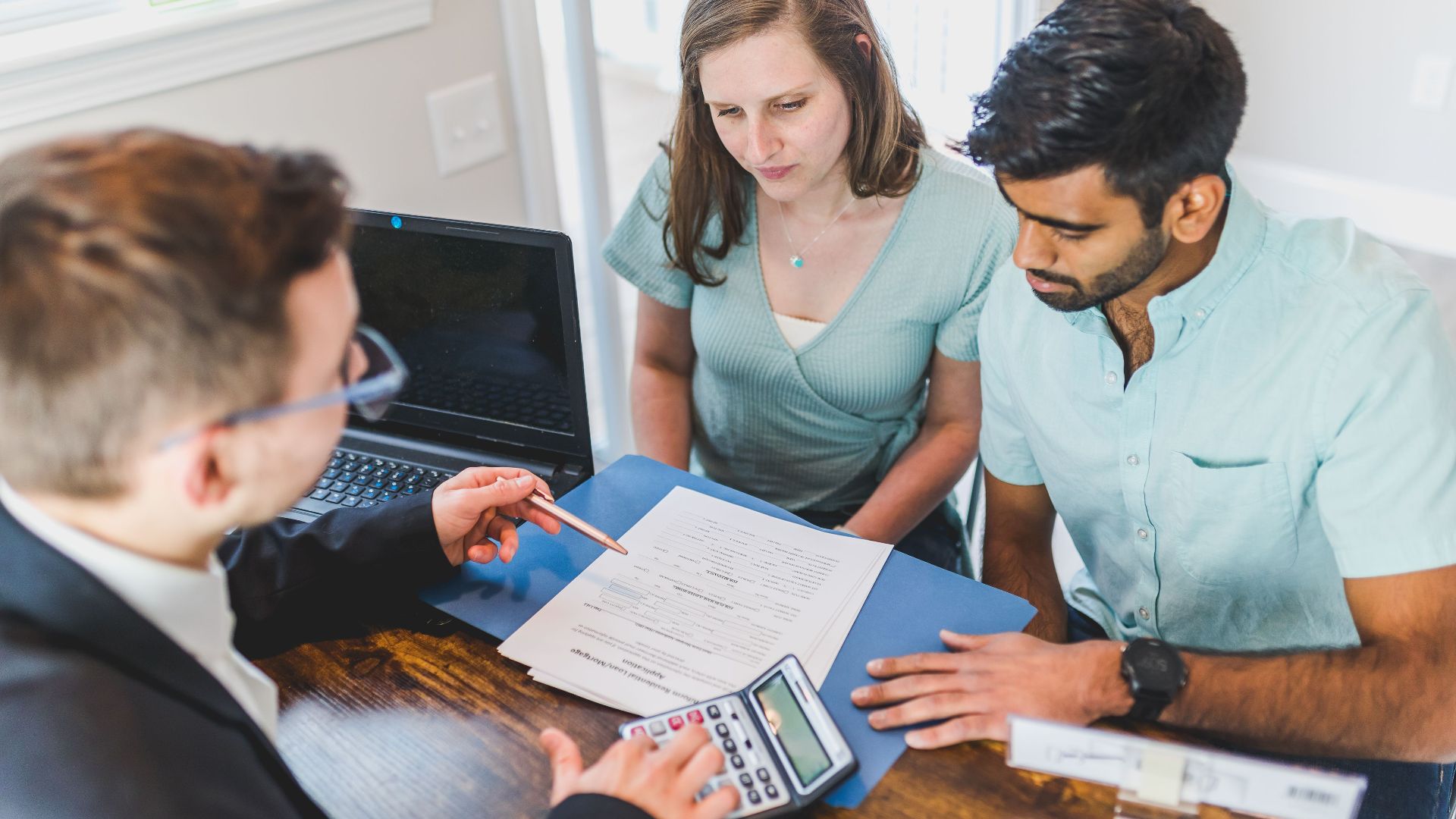 Young couple meeting with real estate agent to discuss property purchase.