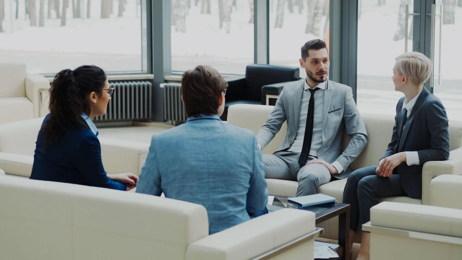 Group of professionals having a discussion in a bright office lounge.