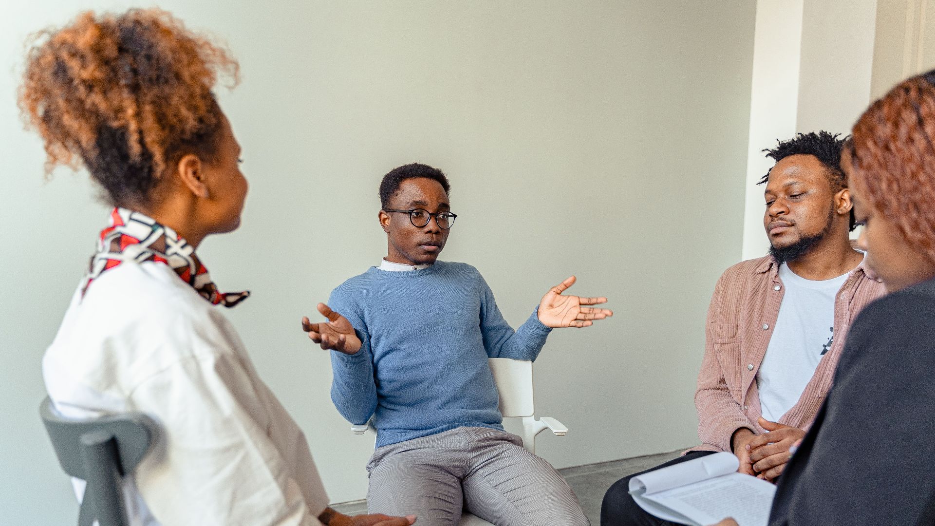 Diverse group therapy session with young adults and a mental health professional indoors.