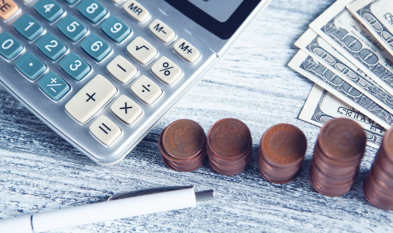 a calculator, pen, and money on a table