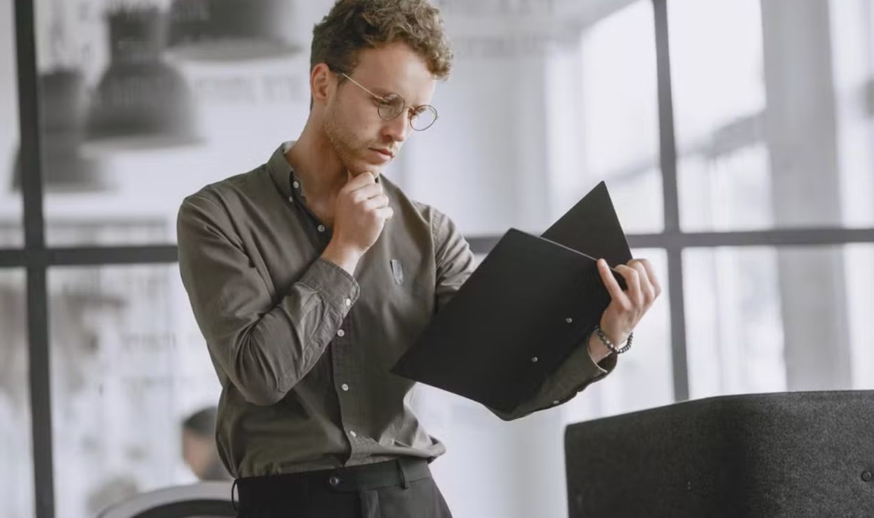 Business professional analyzing documents in a modern office setting, wearing eyeglasses