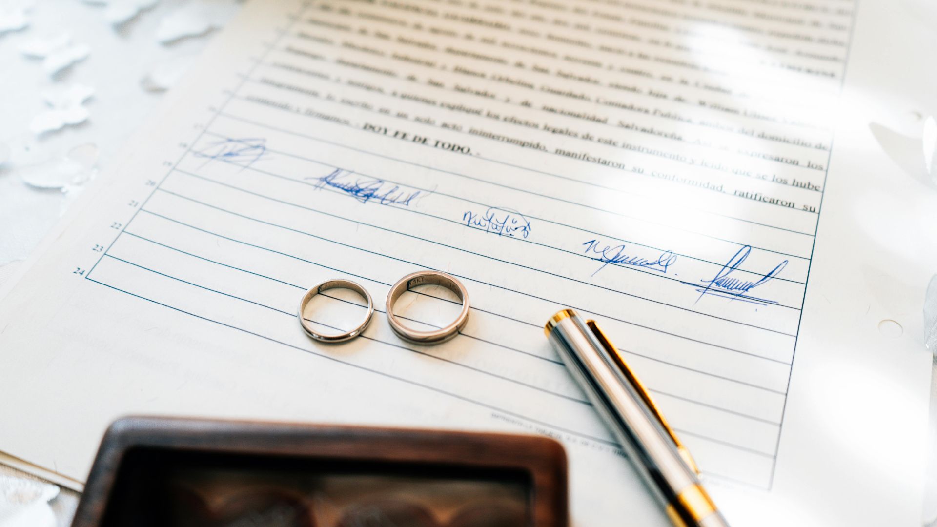 Elegant wedding rings laid on a signed marriage certificate, symbolizing commitment.