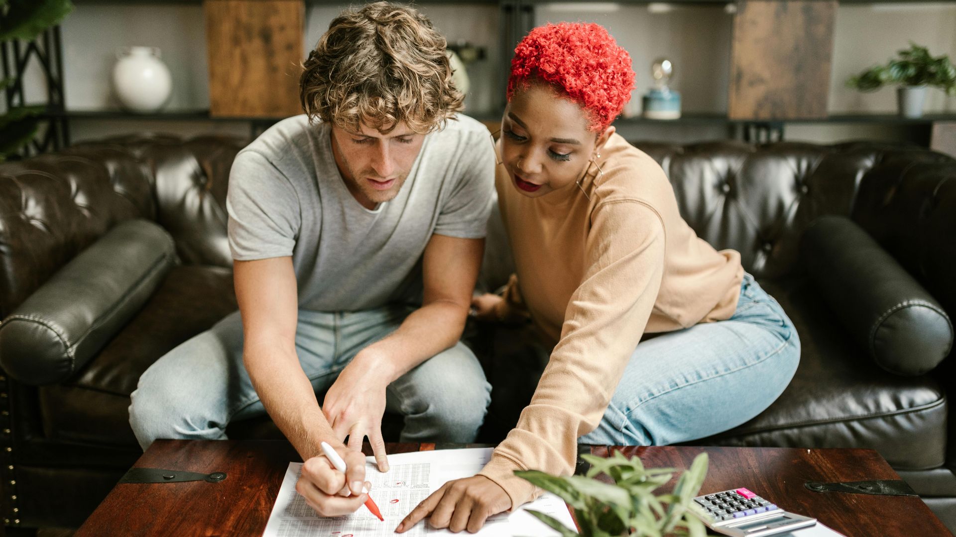 A man and woman collaborating on a project at home, focusing on paperwork.