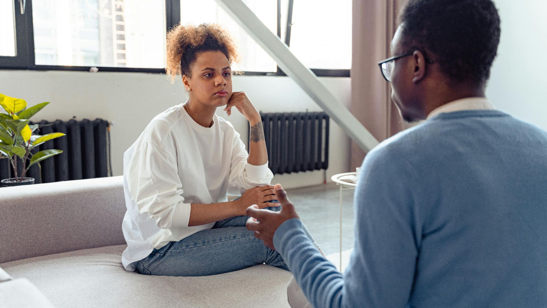 Two individuals engaged in a thoughtful therapy session indoors.