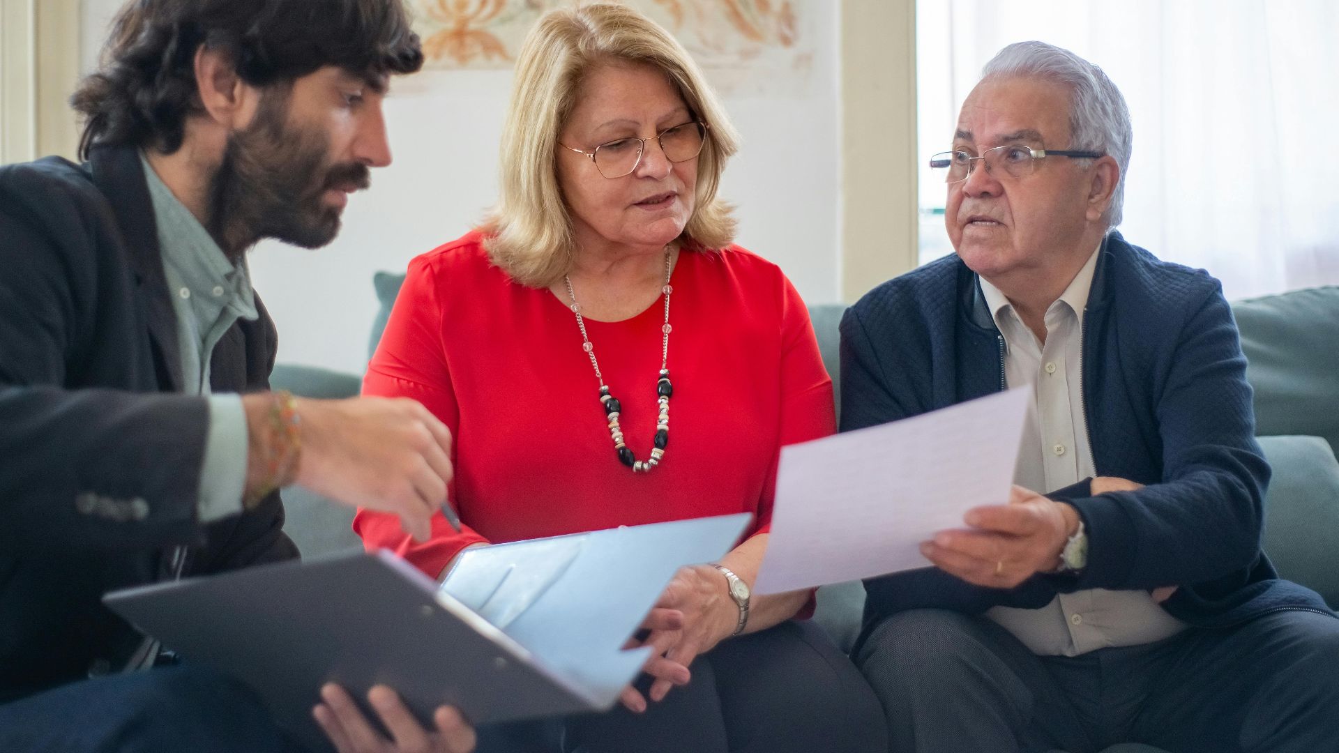 Senior couple consulting with a professional advisor, discussing documents indoors.