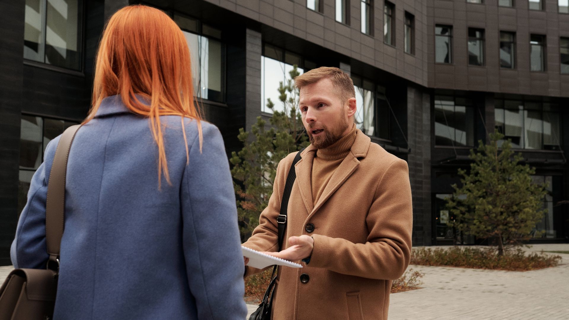 Two business professionals in conversation outside an urban office building.