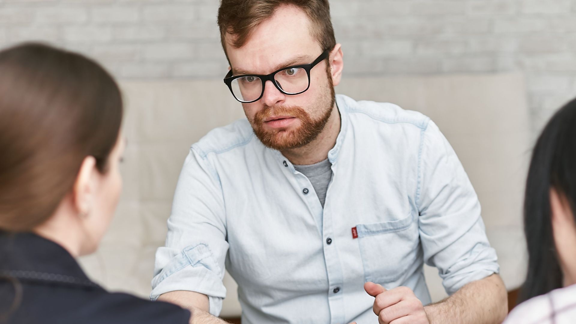 Group of adults engaged in a focused work meeting indoors, discussing plans.