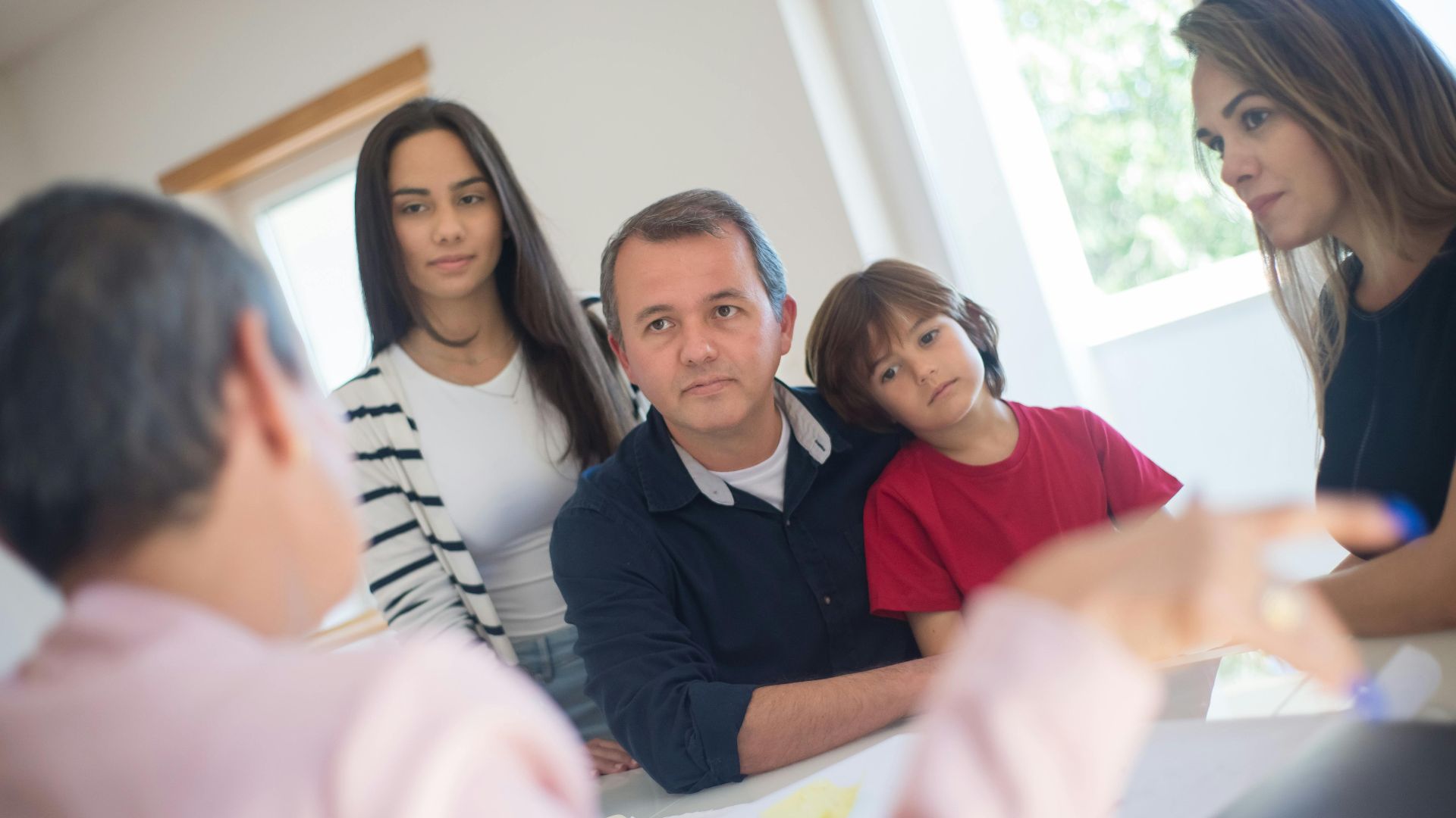 A family of four seeks advice from a professional during an indoor consultation in a bright room.