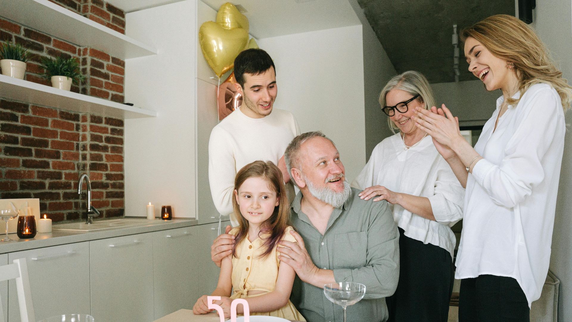 A joyful family celebration indoors with a birthday cake and balloons marking the 50th milestone.
