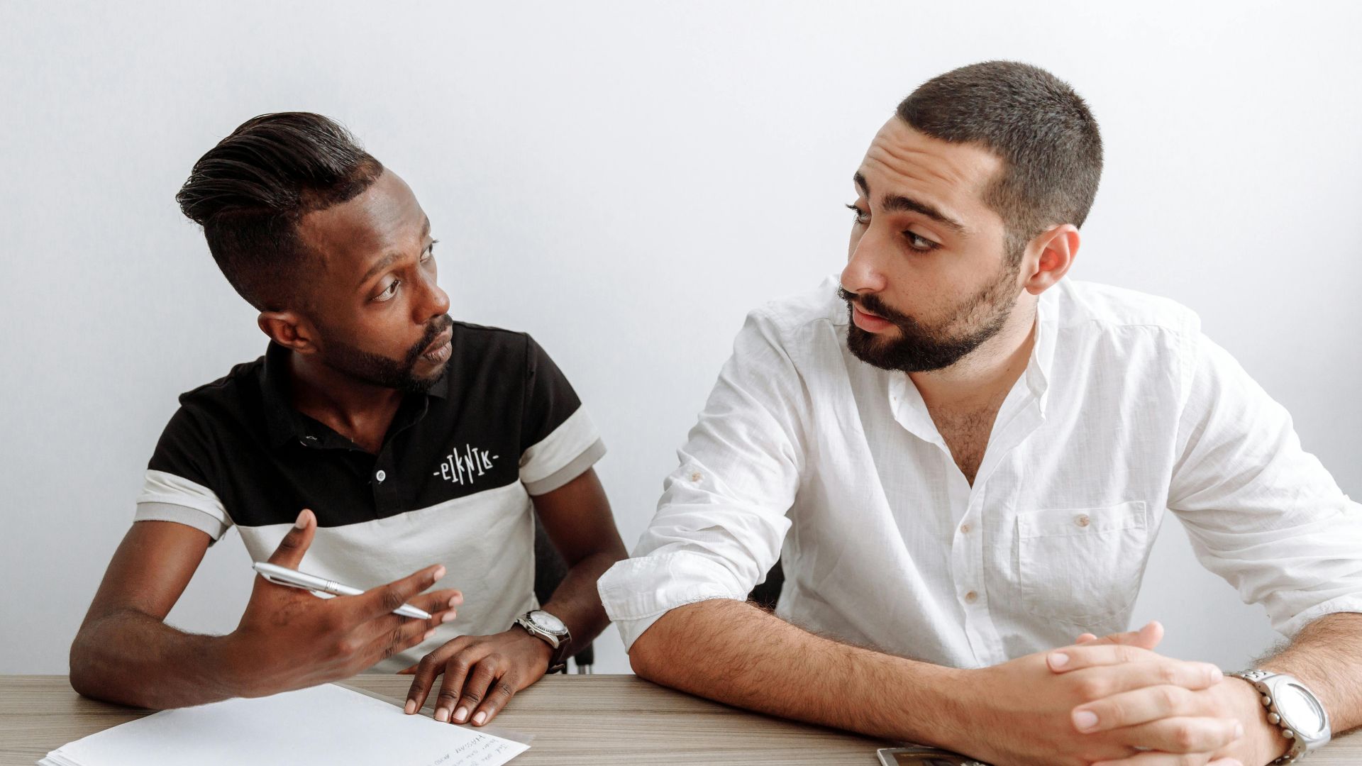 Two diverse men engage in a serious office discussion, emphasizing collaboration and teamwork.