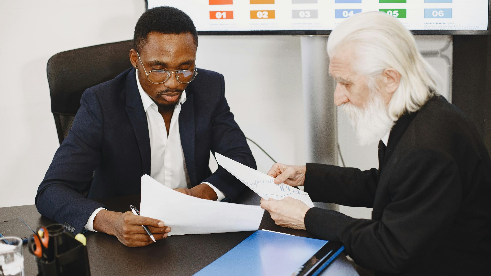 Two businessmen in a meeting discussing documents, focusing on a diverse team engagement.