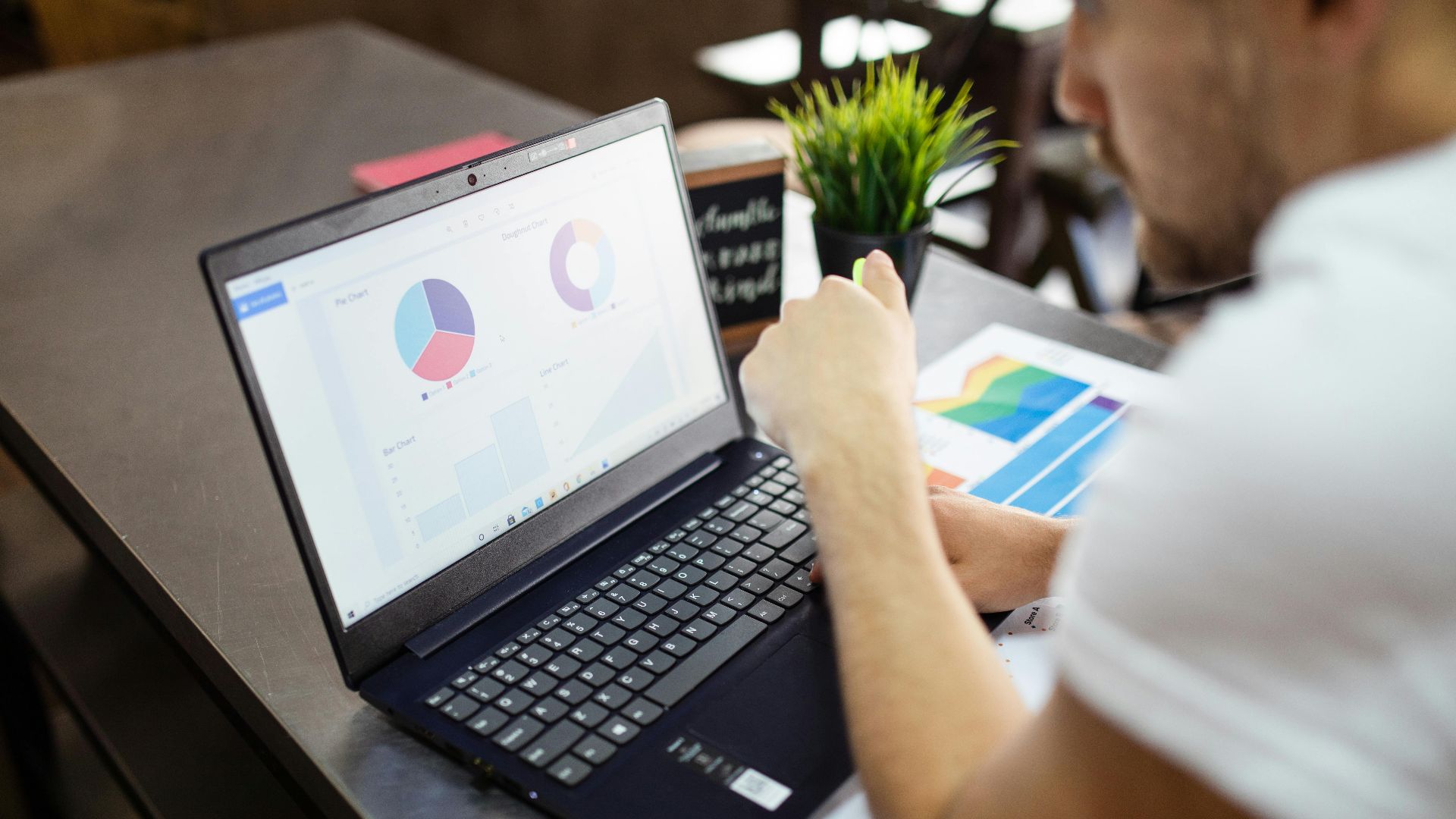 Man reviewing charts and graphs on a laptop for business analysis.