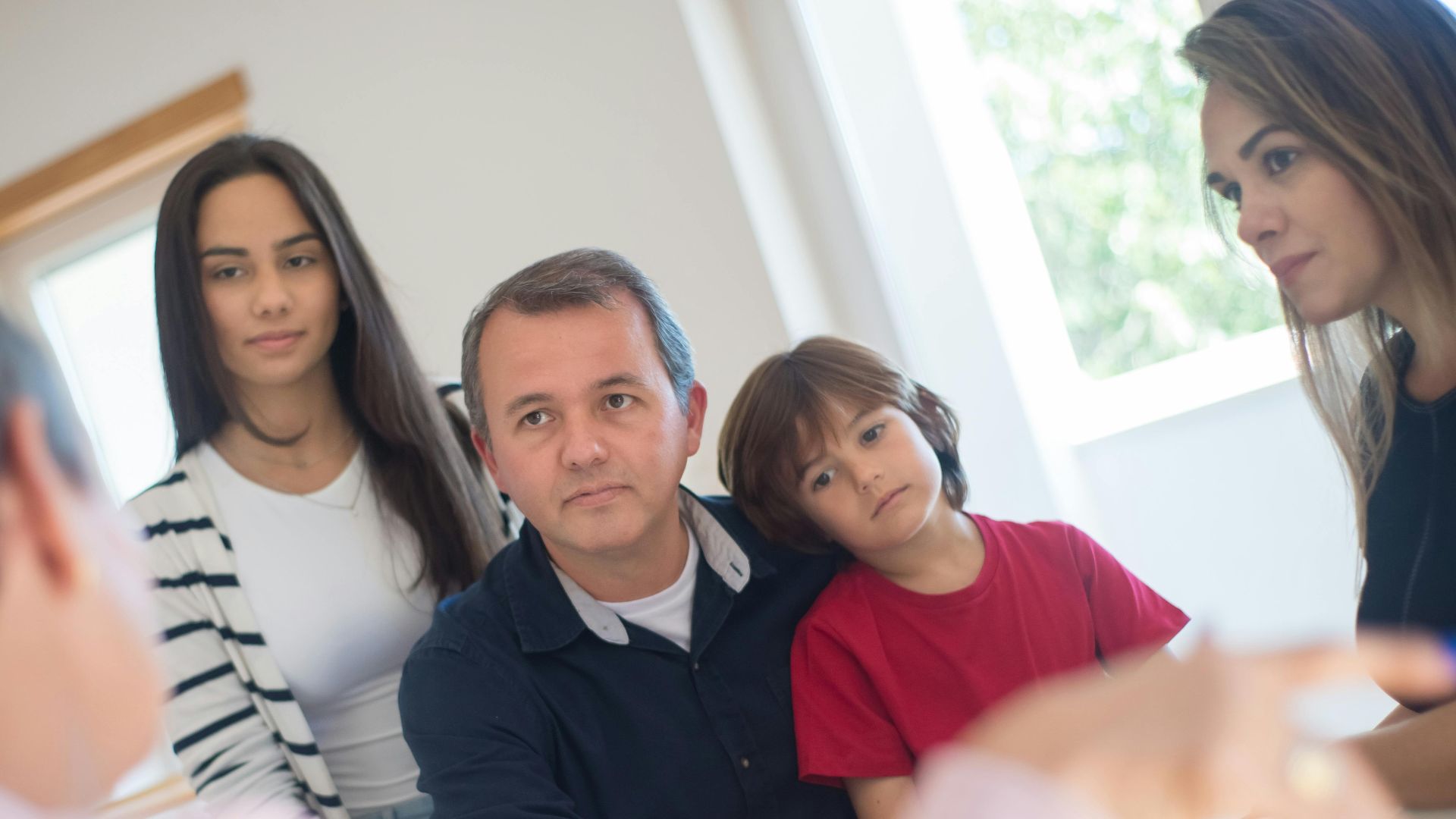 A family of four seeks advice from a professional during an indoor consultation in a bright room.
