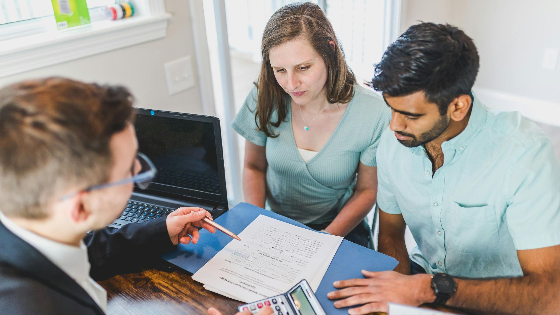 Young couple meeting with real estate agent to discuss property purchase.