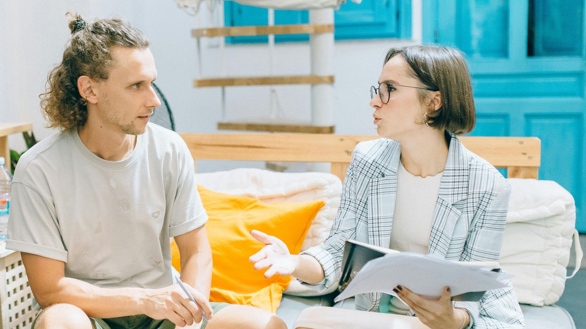 A man and woman discussing work in a stylish, bright living room setting.