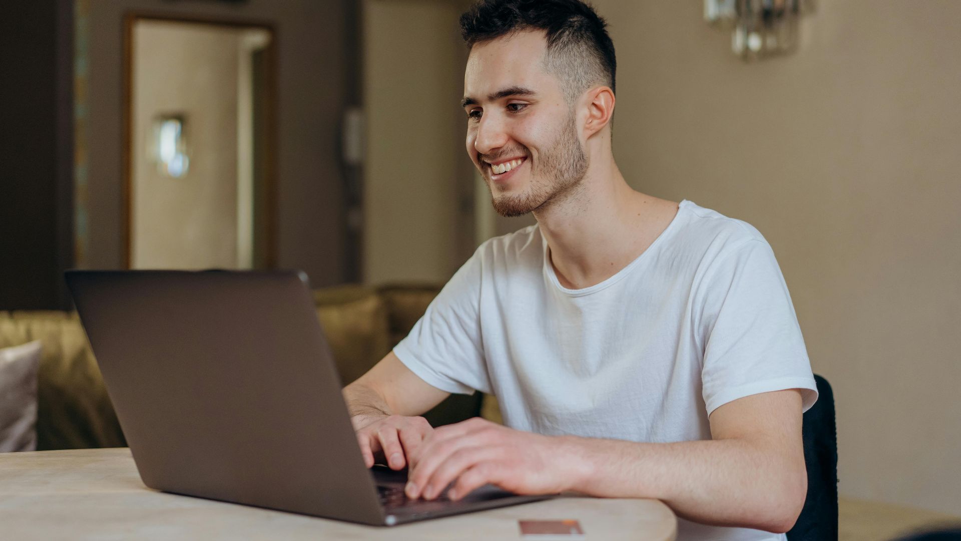 Young man smiling while online shopping with laptop indoors at home.