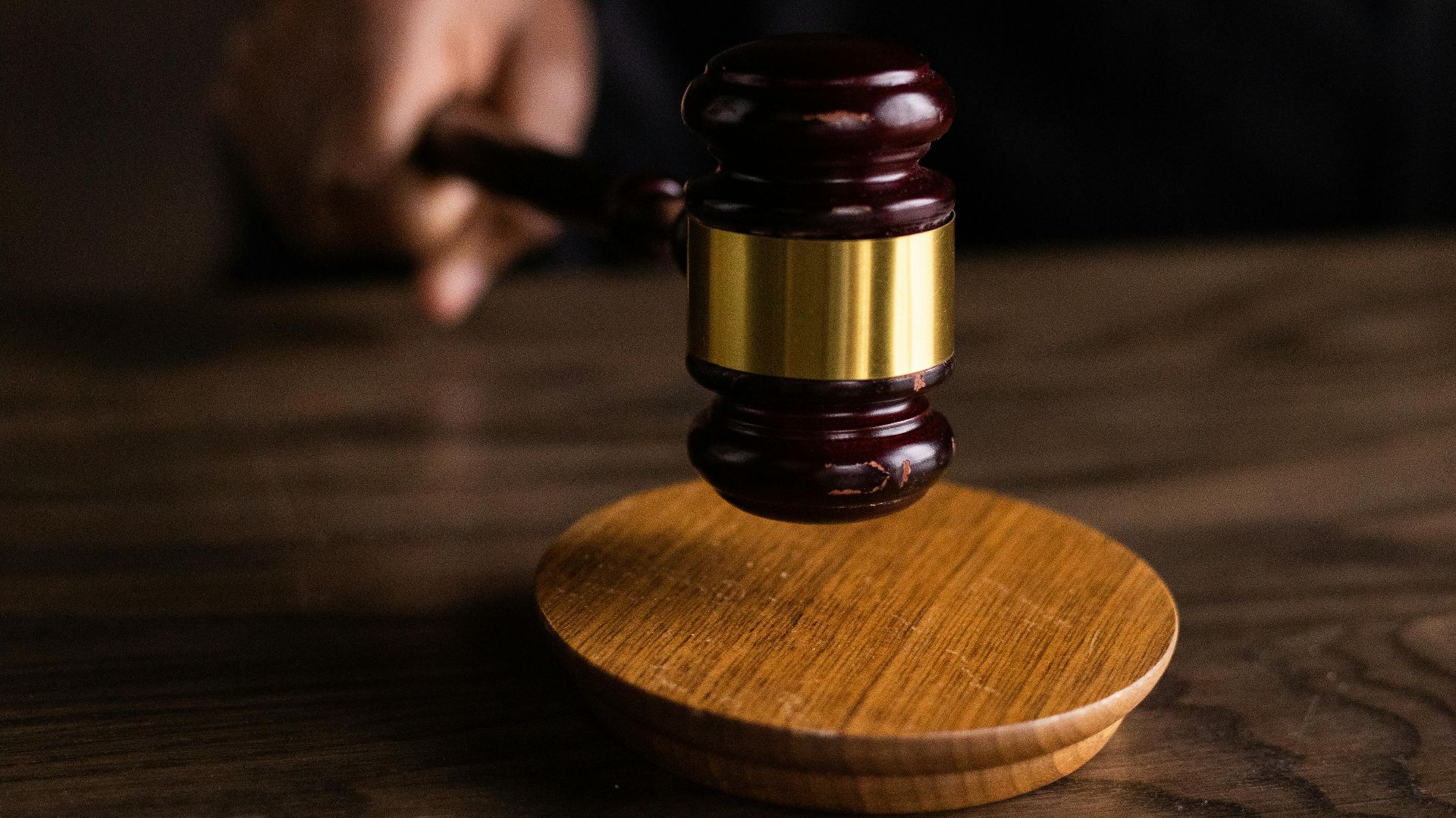 A gavel striking a sound block, symbolizing justice and legal authority in a courtroom setting.