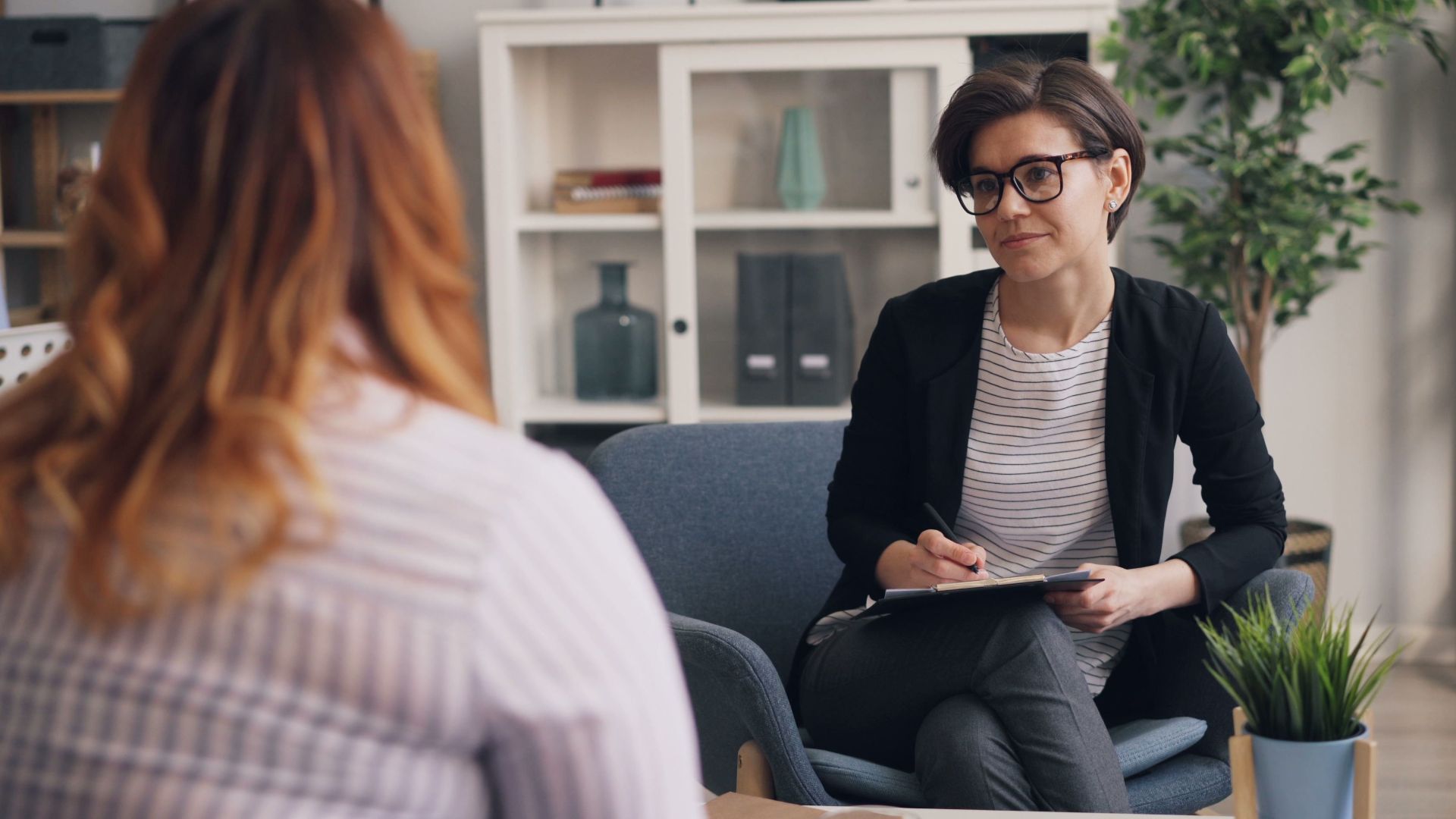 A therapist and patient having a counseling session in a modern office sitting area.
