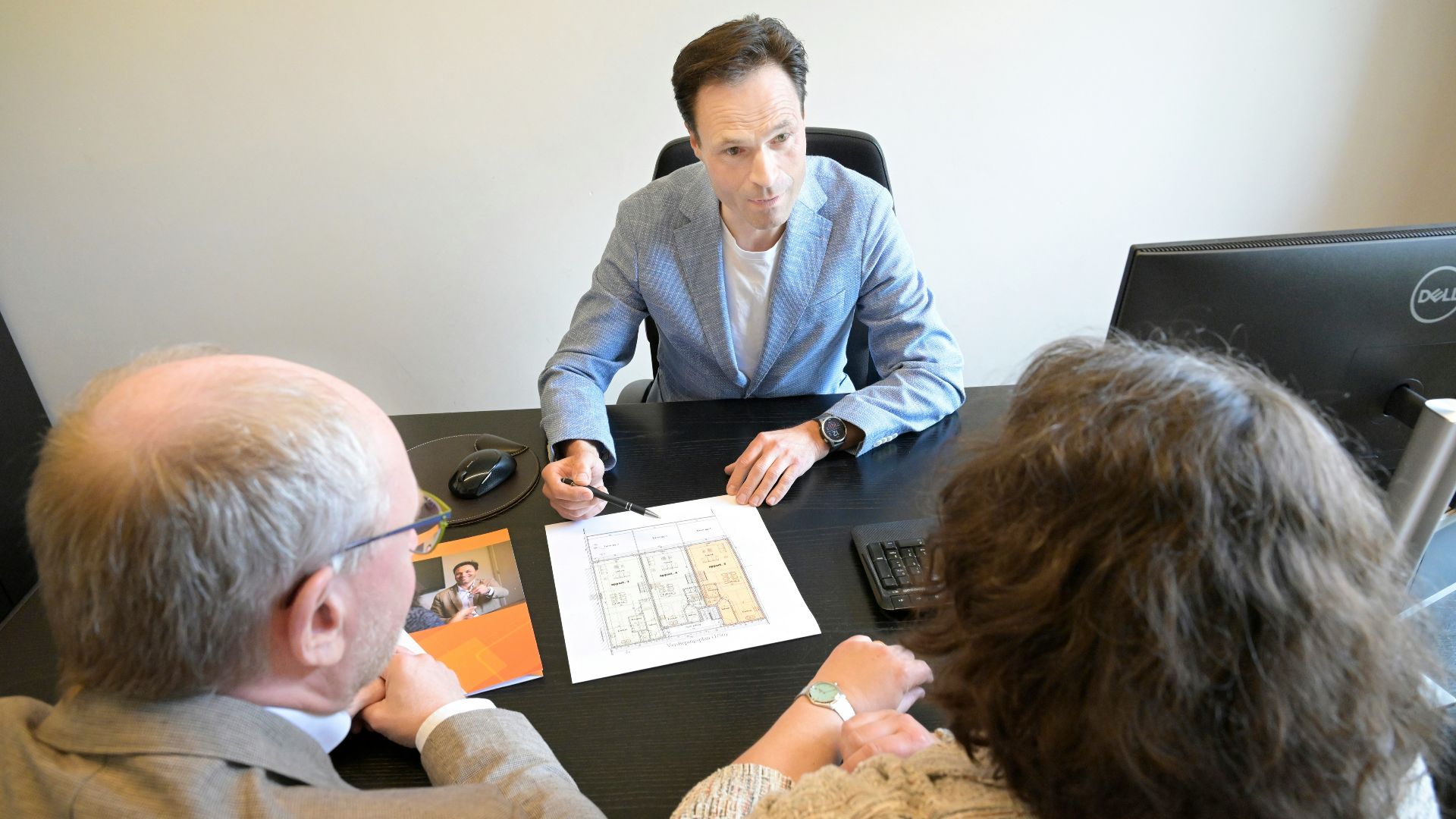 Consultant explains plans to a couple during a business meeting.