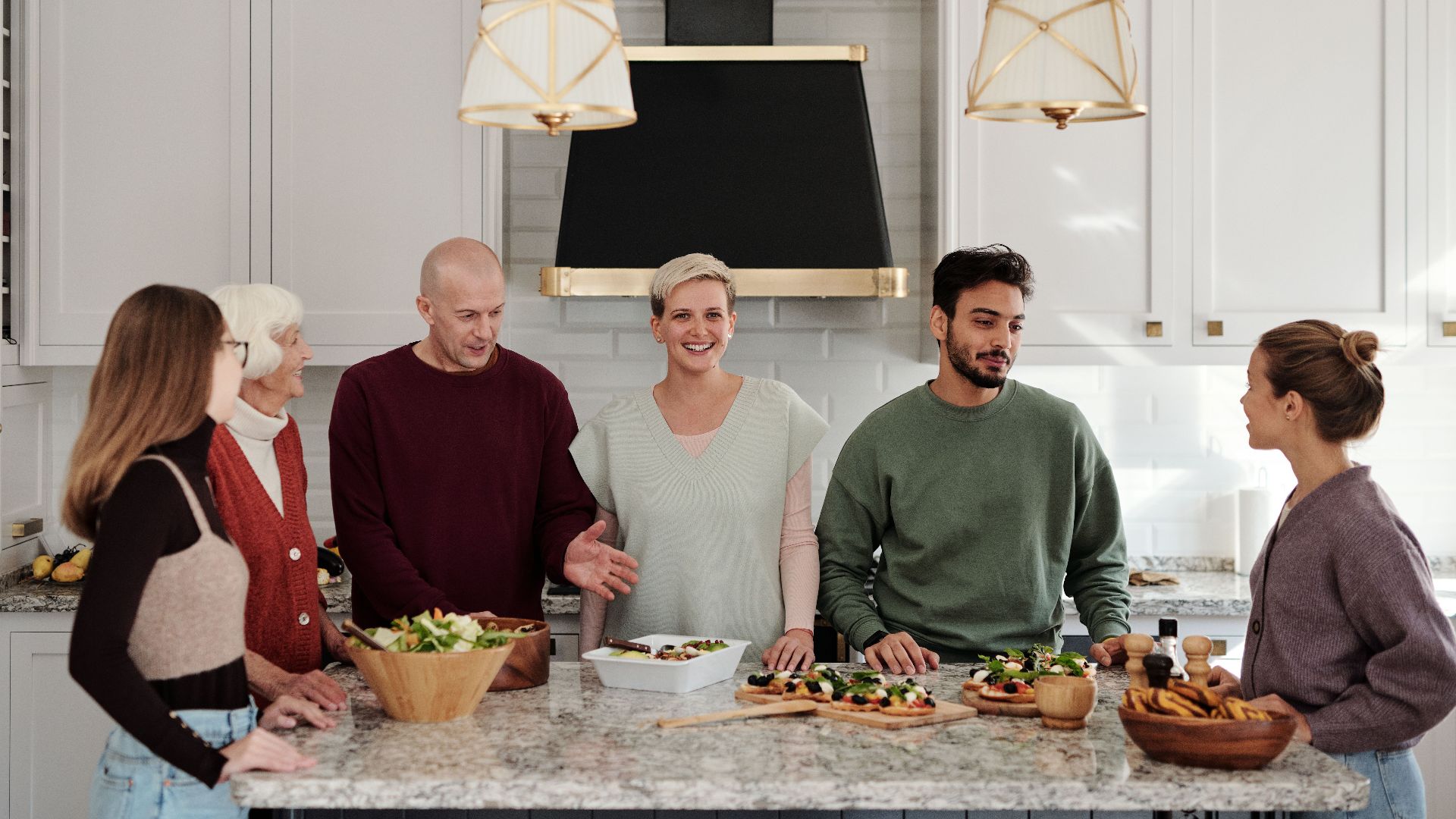 A multi-generational family enjoying a meal preparation together in a bright kitchen.
