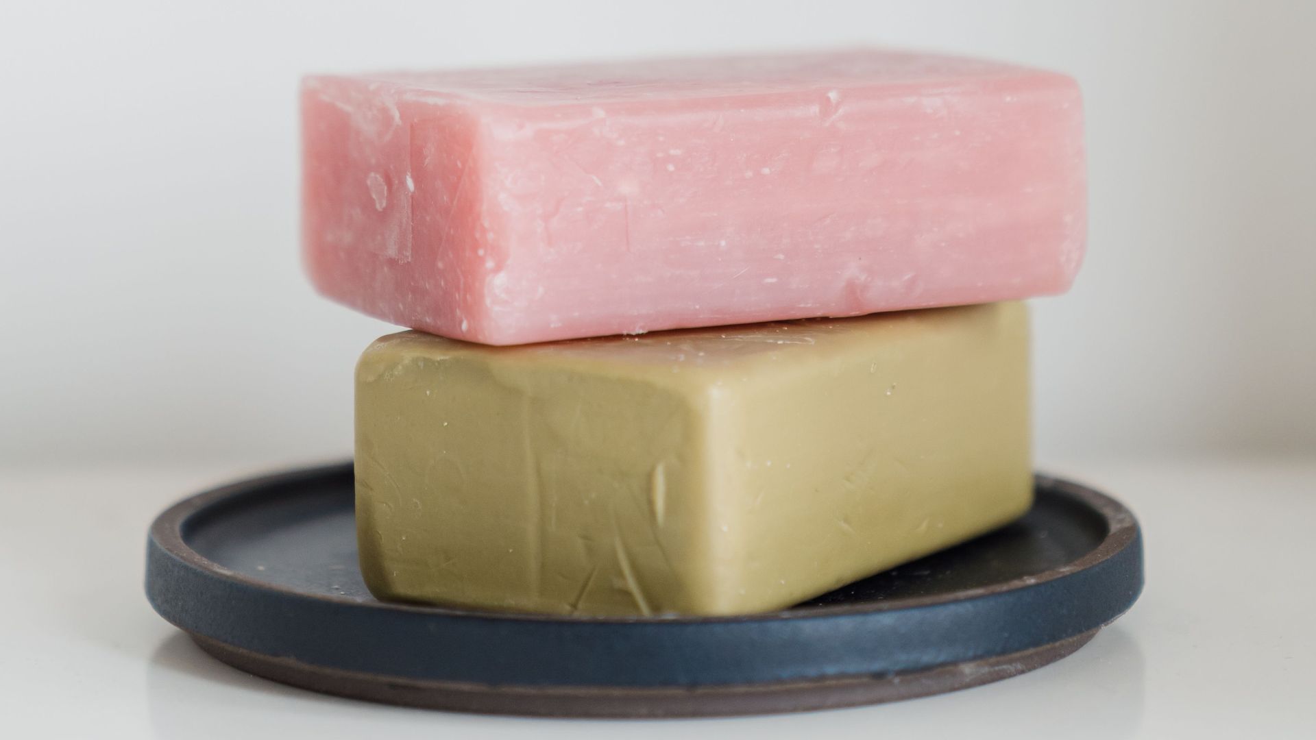 Two soap bars neatly stacked on a tray against a white background.