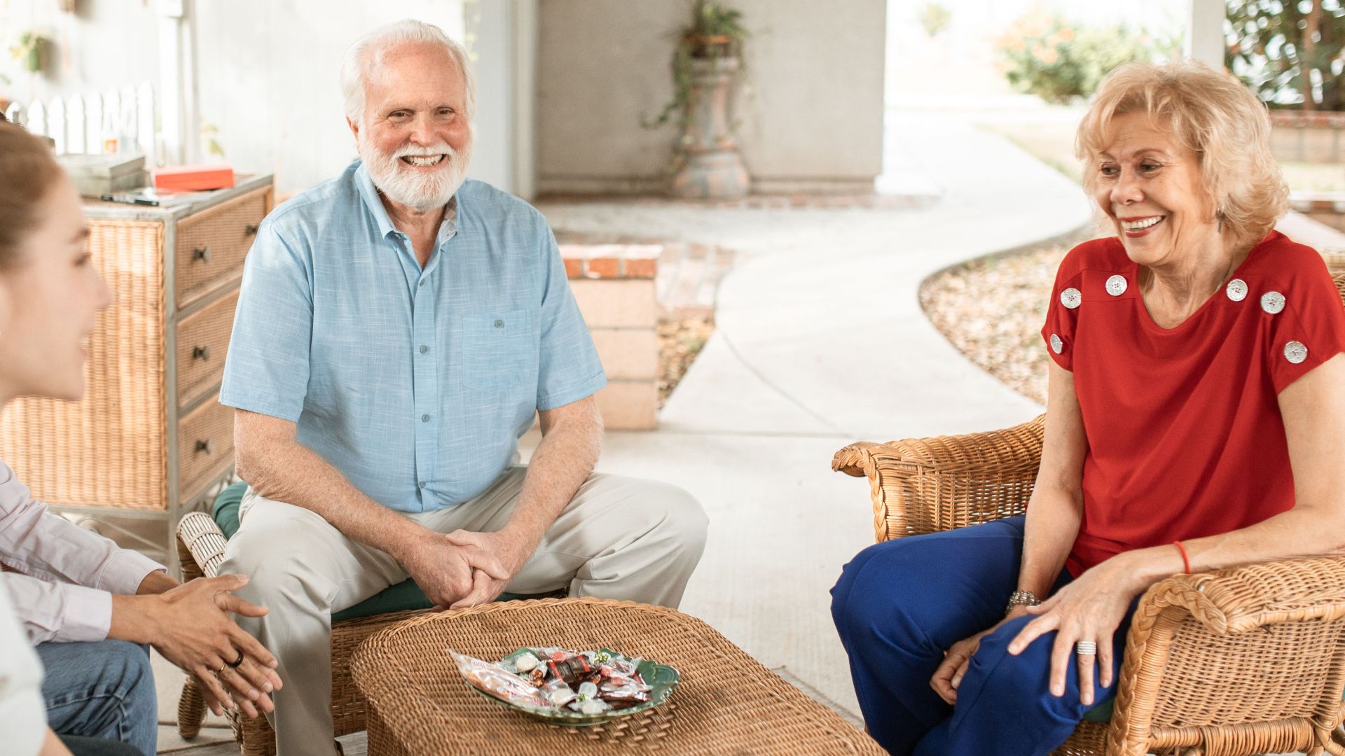 Family enjoying a relaxed conversation on a cozy outdoor patio with natural light.