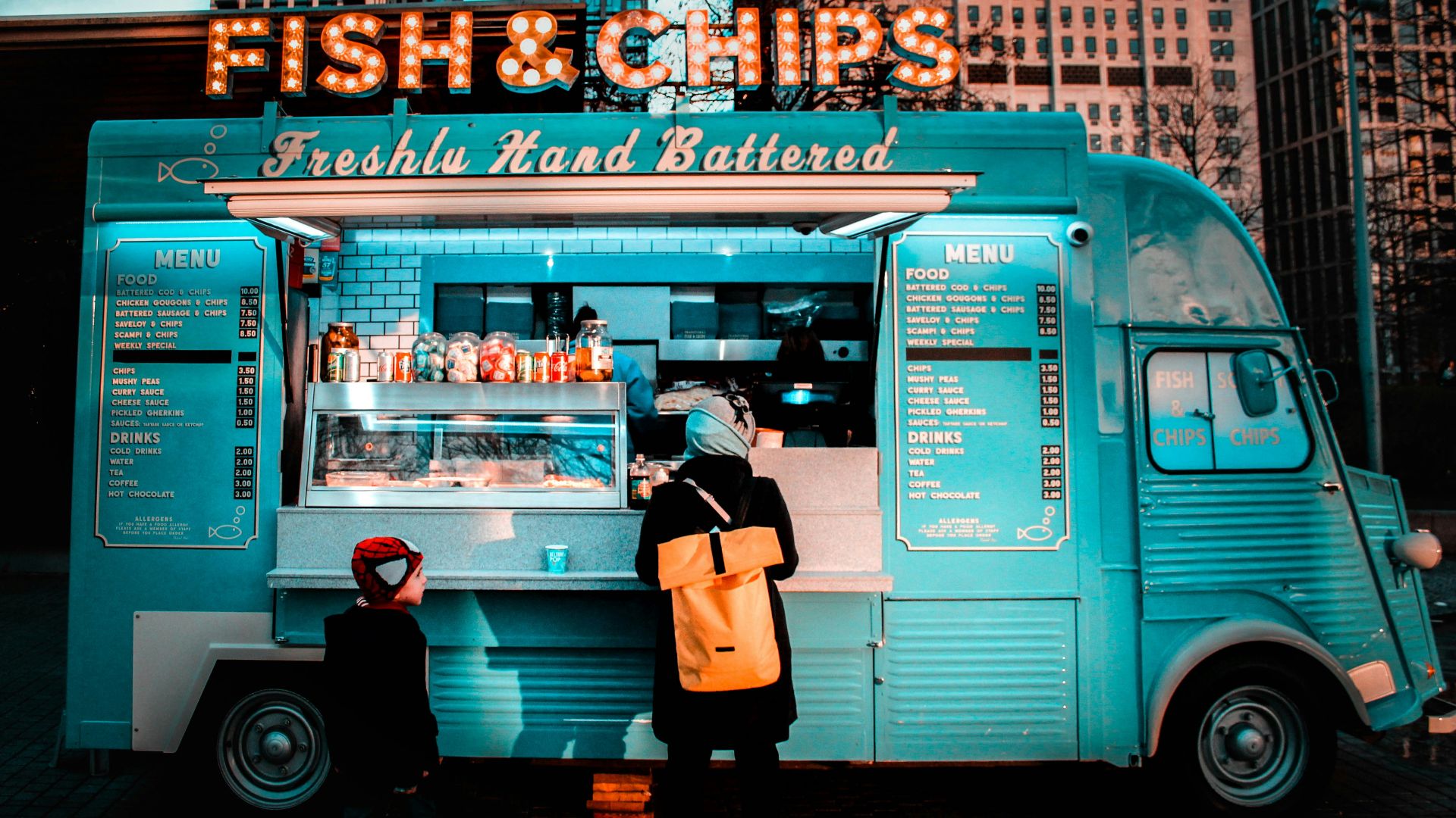 woman in brown coat standing in front of food stall