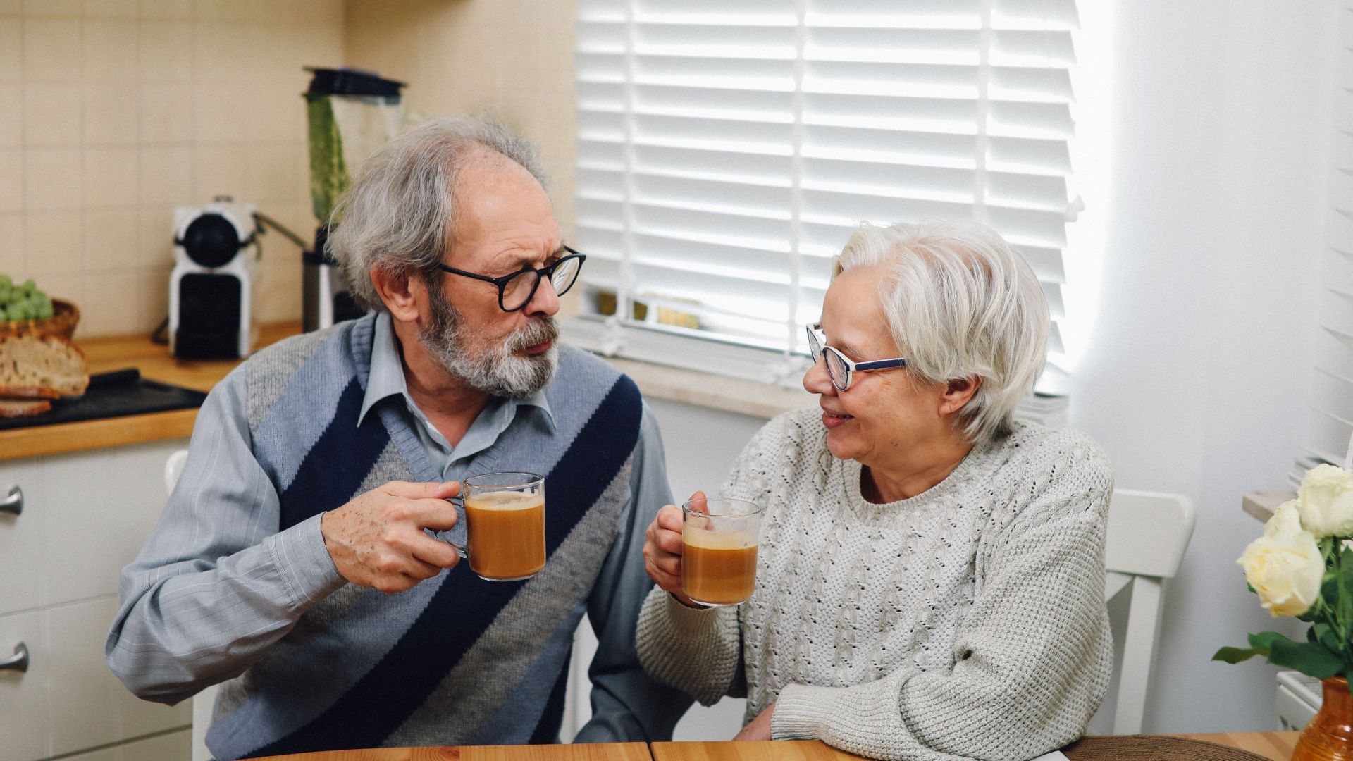 Senior couple enjoying coffee together at home in cozy kitchen setting.
