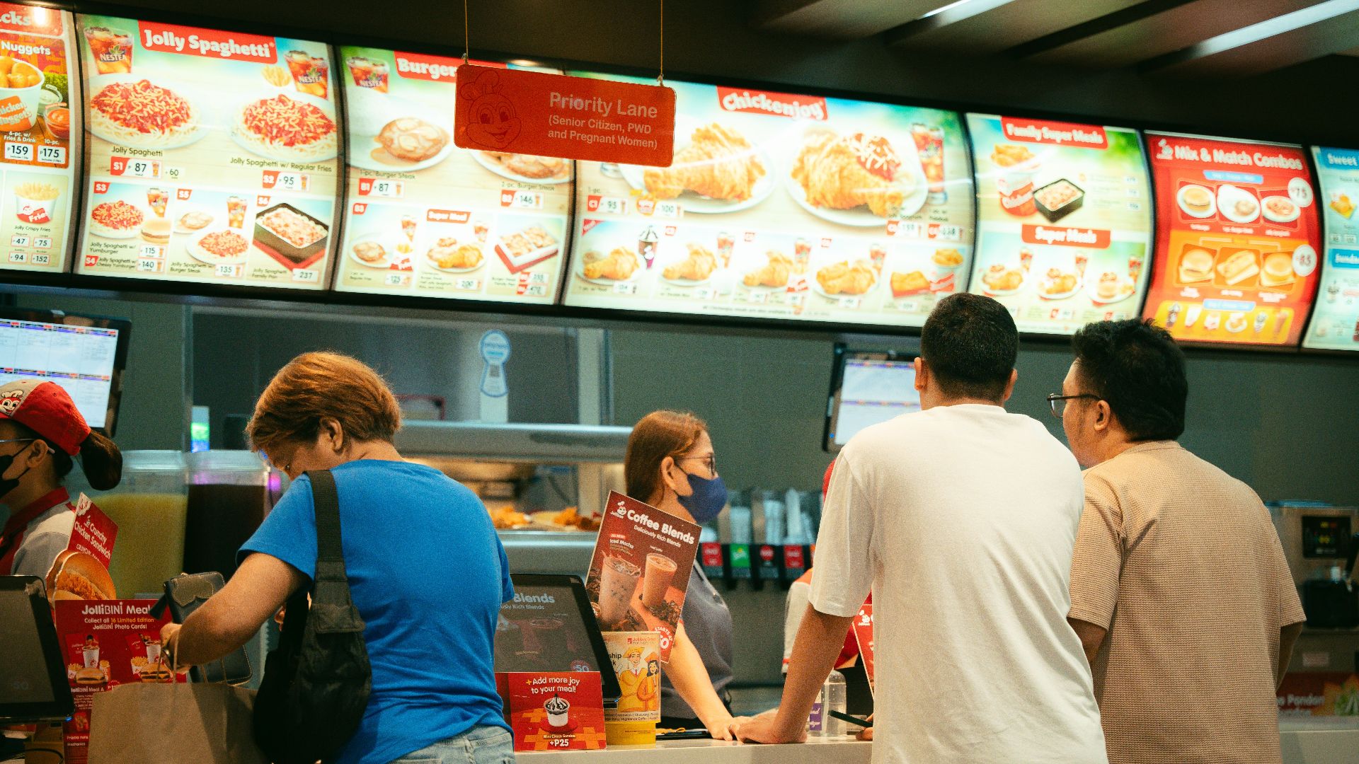 Customers ordering food at a fast food restaurant counter. Busy atmosphere.
