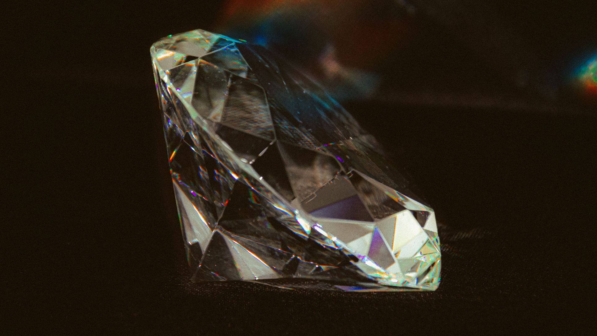 Stunning close-up of a diamond gem with prismatic reflections on a dark surface.