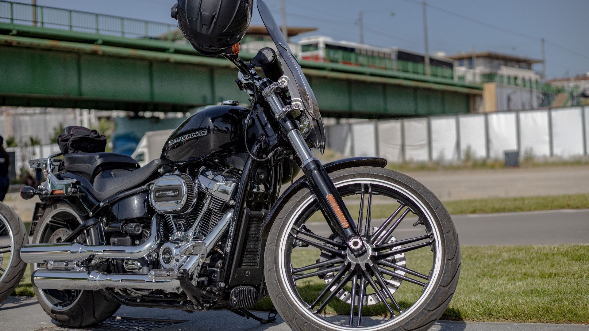 A stylish black Harley Davidson motorcycle parked outdoors with a helmet on the handlebars.