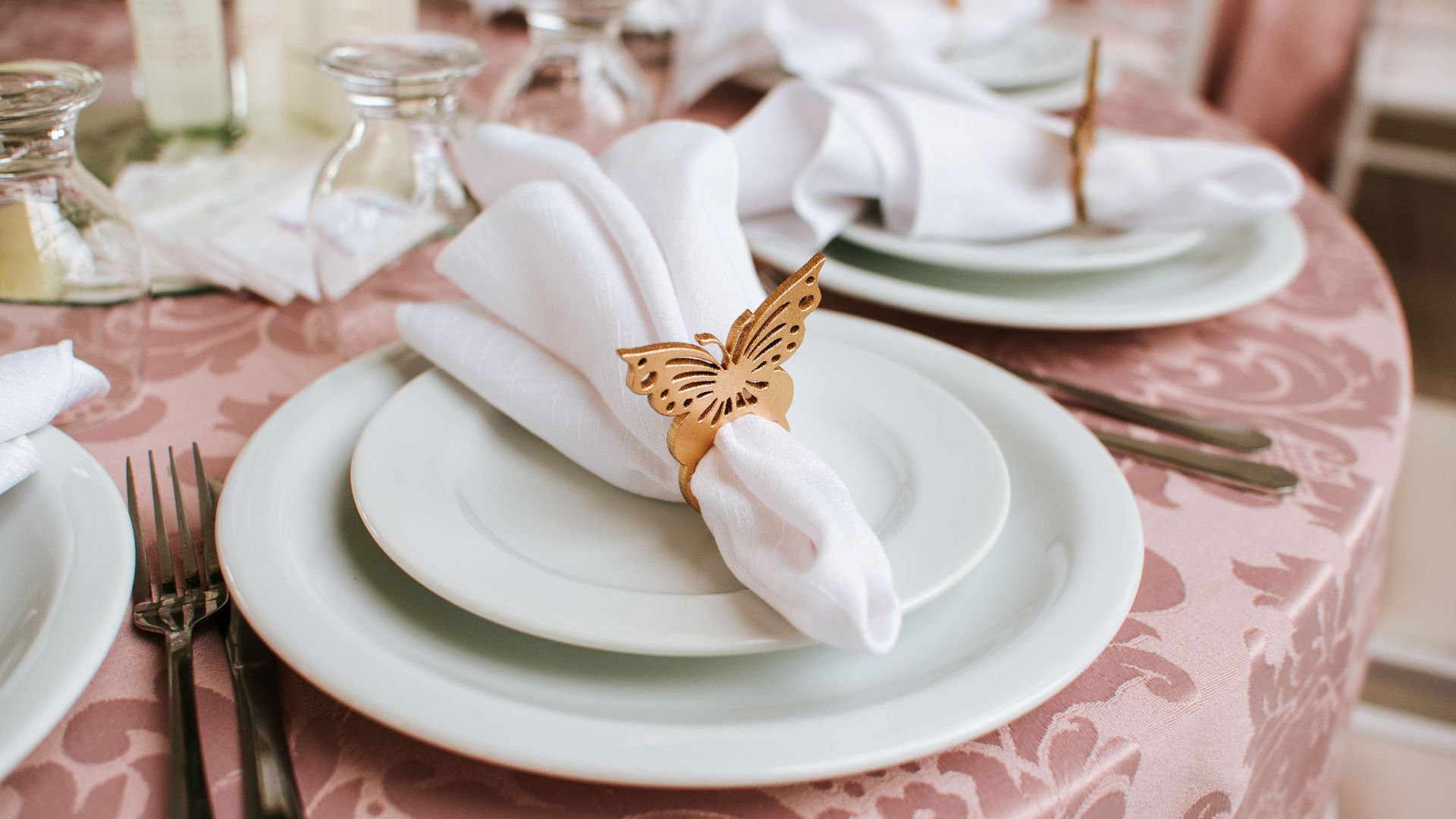 Sophisticated wedding table setting featuring butterfly napkin rings, fine china, and elegant tableware.