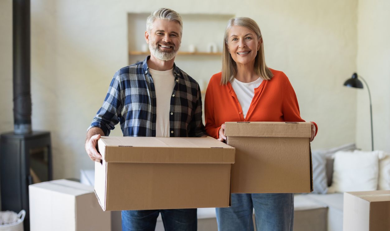 Couple enjoying moving into new home holding boxes