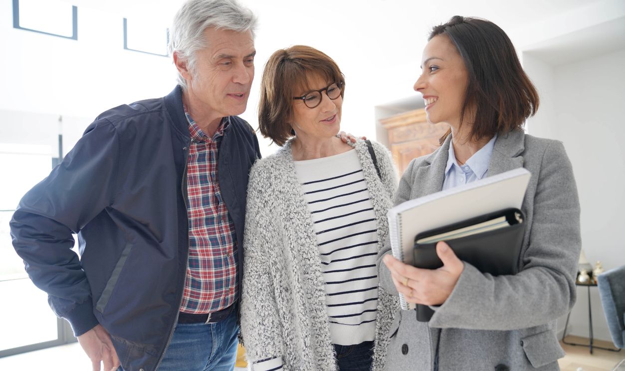 Senior couple with real estate agent visiting contemporary house