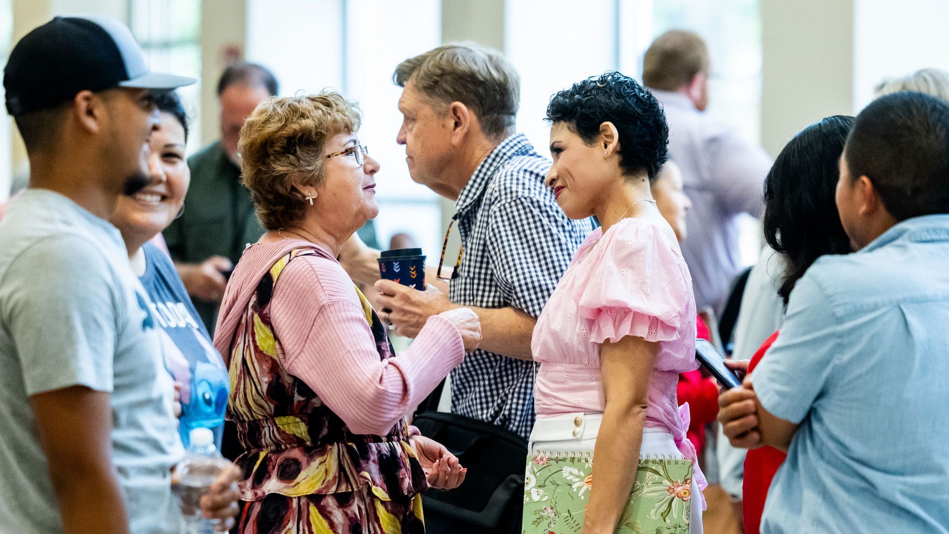 A diverse group of people engaging in conversation at an indoor gathering.