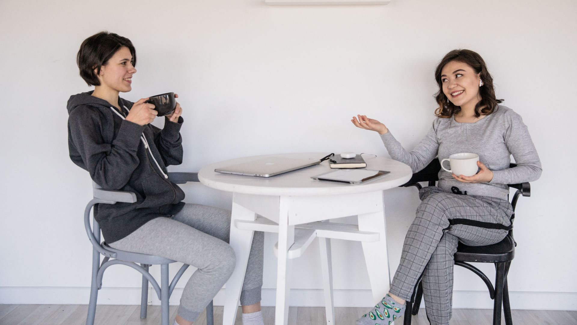 Two women enjoying a friendly chat over coffee indoors, relaxed and smiling.