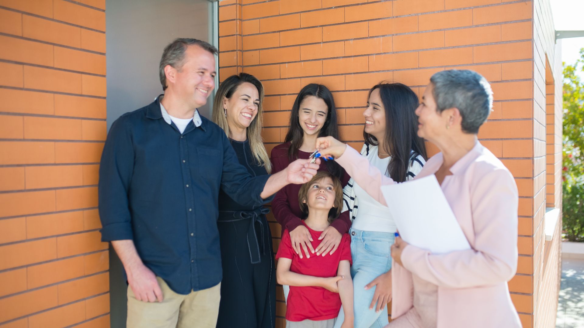 Family joyfully receiving keys to their new home outdoors, symbolizing real estate success.
