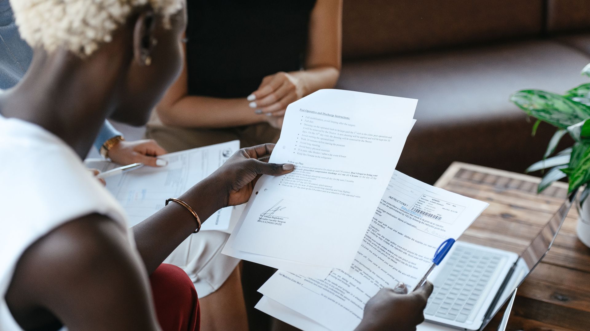 From above of crop anonymous African American female comparing data in papers at table of office